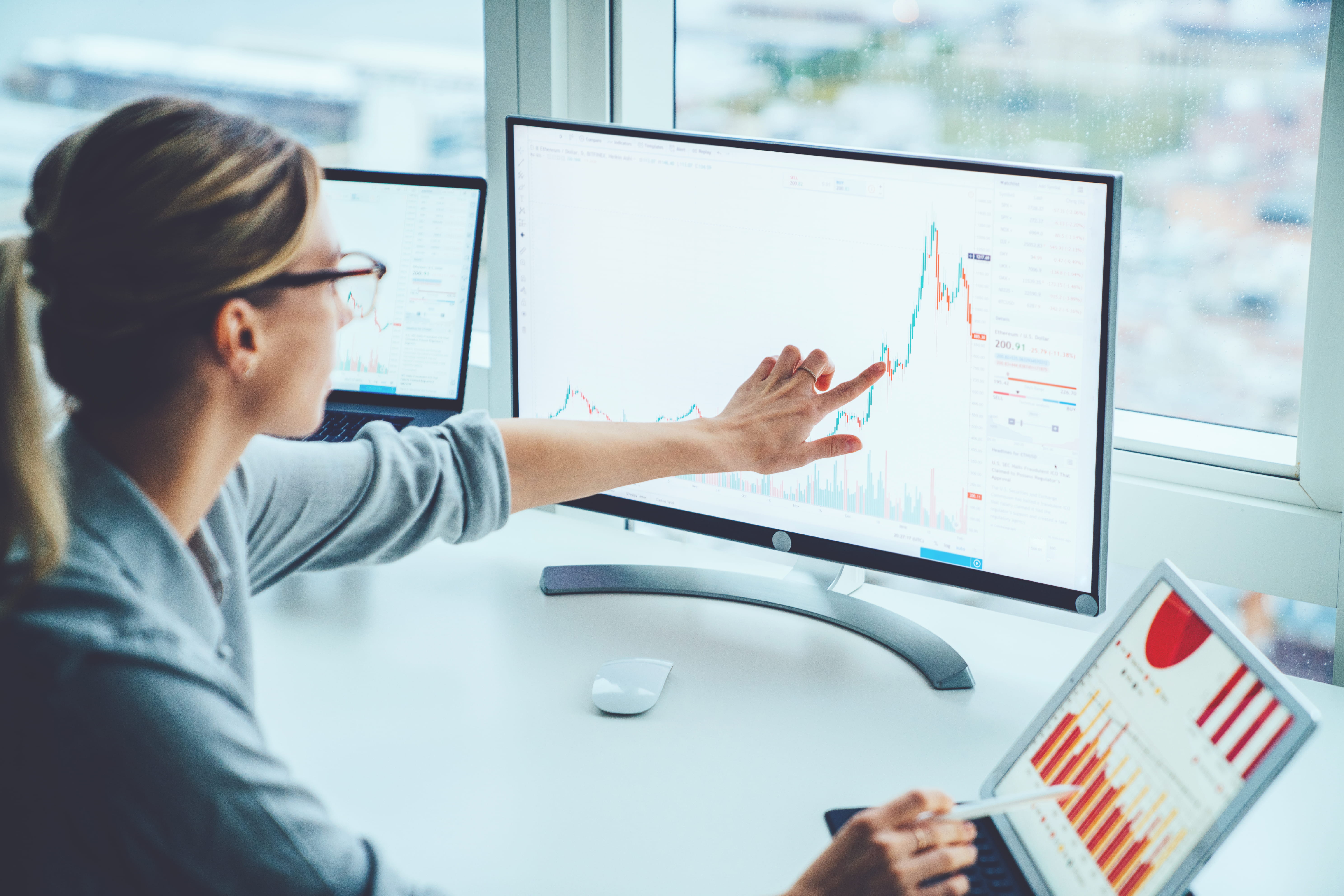 Des analystes financiers de l’une des cinq grandes banques canadiennes consultent des données sur des portefeuilles de placement et l’économie sur une tablette numérique.